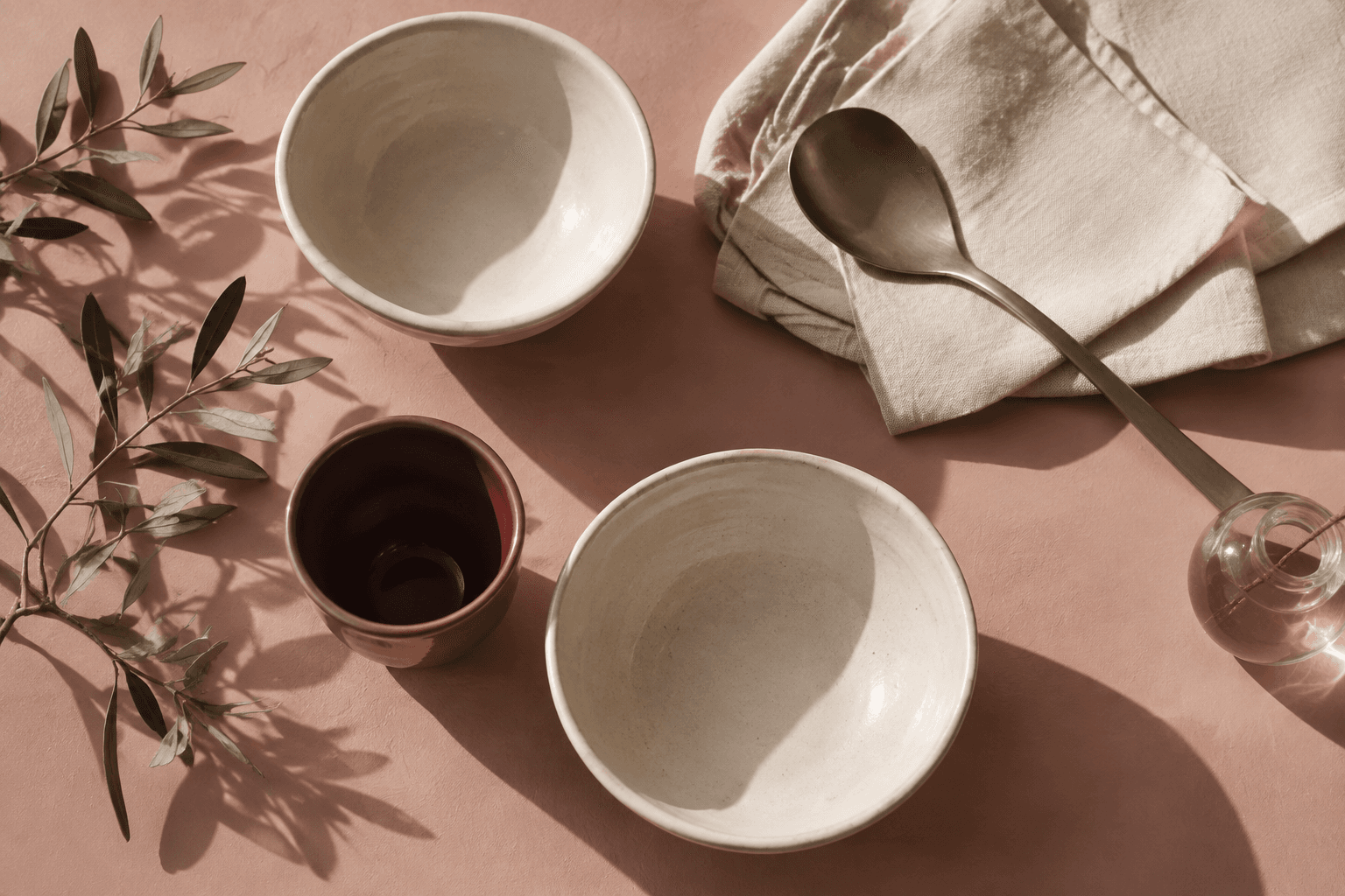 Handmade ceramic bowls and linen on a rose pink table